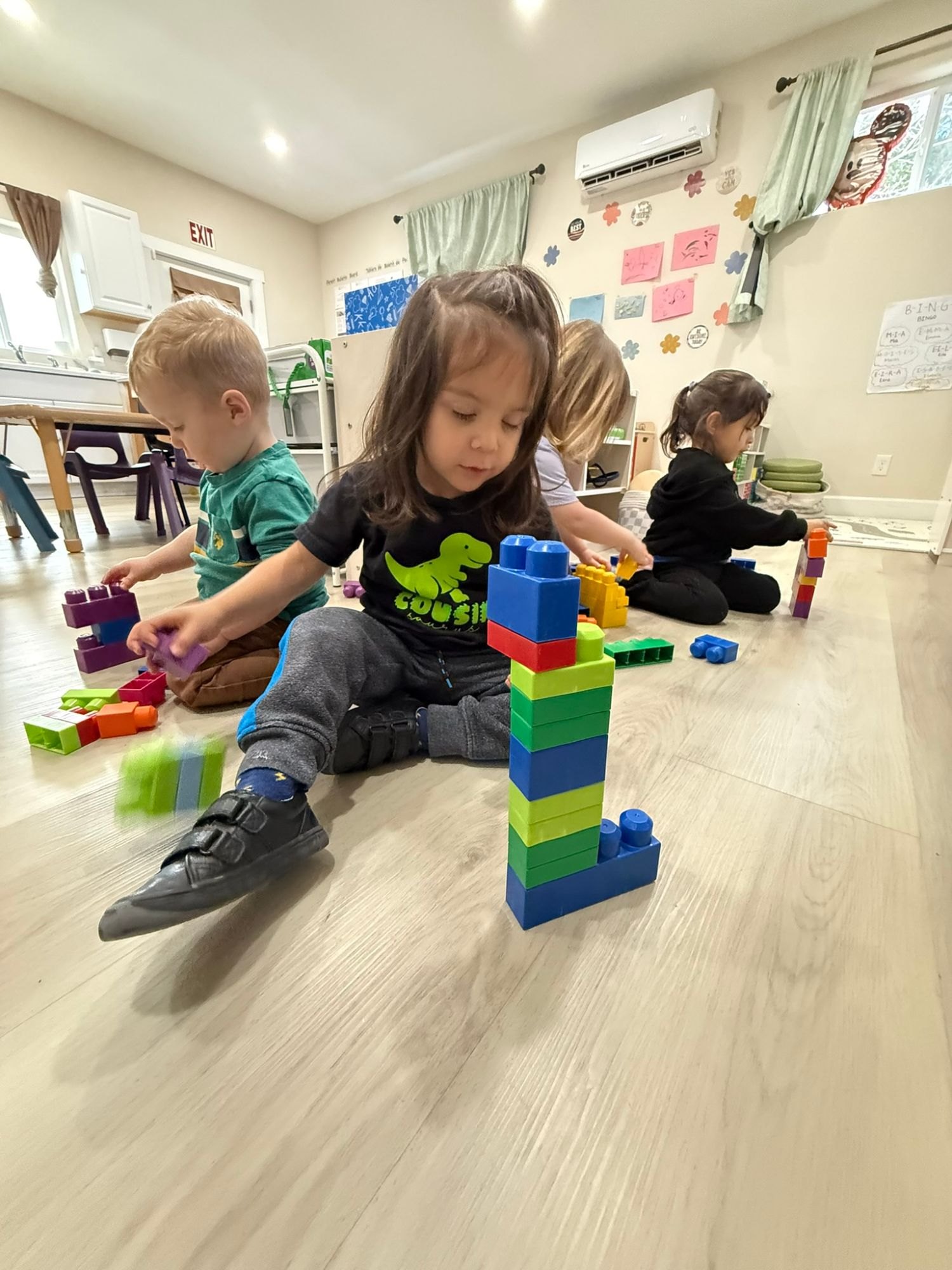 A toddler sitting next to a tall tower of big plastic blocks