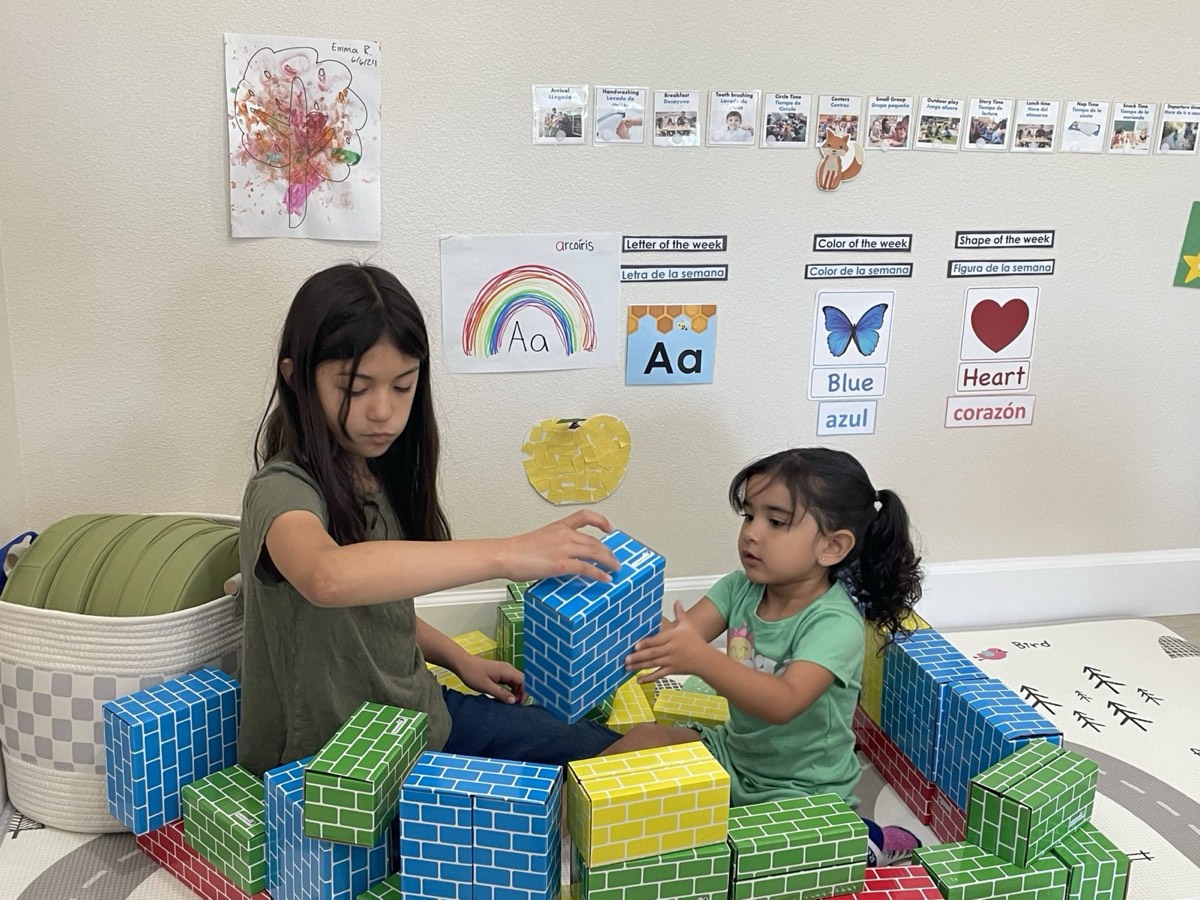 Two girls stacking large brick-pattern blocks