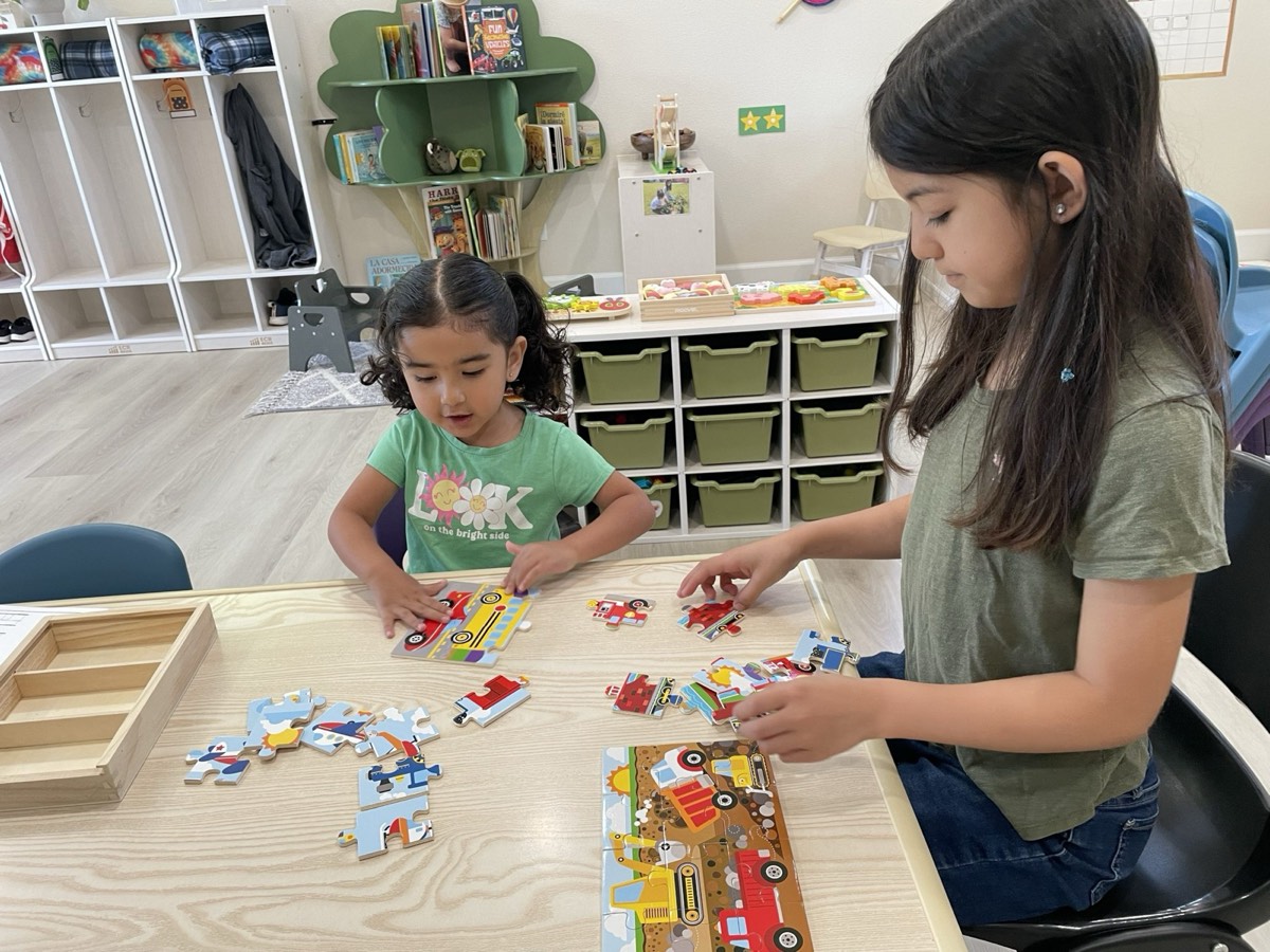 Two girls putting together a vehicle puzzle