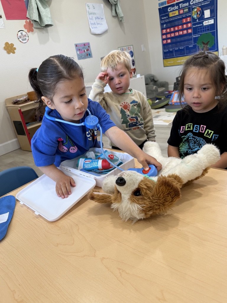 Three children playing vet with a toy stethoscope and a stuffed puppy
